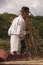 HRUSOV, SLOVAKIA - AUGUST 16: Old farmer in traditional costume fills the thresher during folklore festival Hontianska Parada on Royalty Free Stock Photo