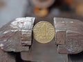 hryvnya coin clamped in a metal vise. Currency and Ukrainian economy under the onslaught