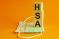 HSA word is written on wooden cubes lying on a medical mask. Concept wooden blocks. Health Savings Account Royalty Free Stock Photo