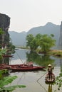 Scenic, serene countryside scenery at Van Lam Village, Vietnam with fisherman wearing hat roaring the small wooden boat standing