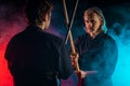 Two kendo fighters opposite each other with shinai isolated over dark space Royalty Free Stock Photo