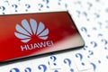 HUAWEI logo on the HUAWEI smartphone and a lot of paper question marks around. The conceptual photo about future of the tech giant