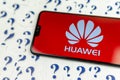 HUAWEI logo on the HUAWEI smartphone and a lot of paper question marks around. The conceptual photo about future of the tech giant Royalty Free Stock Photo