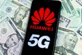 Huawei logo on the smartphone which is placed on the US dollars. Conceptual photo for Huawei profits out their 5G networks