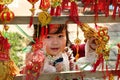 Portrait of little Vietnamese girl in red dress with traditional Vietnamese New Year decorations on the street of city.