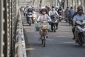 Automobile and pedestrian steel bridge over the river in Hue town, Vietnam. People on motorbikes on the road across the bridge Royalty Free Stock Photo