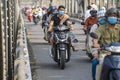 Automobile and pedestrian steel bridge over the river in Hue town, Vietnam. People on motorbikes on the road across the bridge Royalty Free Stock Photo