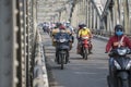 Automobile and pedestrian steel bridge over the river in Hue town, Vietnam. People on motorbikes on the road across the bridge Royalty Free Stock Photo