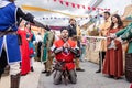 A man dressing as a medieval knight with metallic armor is mading a performance in the parade of