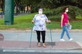 Huelva, Spain - September 10, 2020: Overweight caucasian woman walking with Nordic walking poles wearing protective face mask due