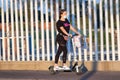 Huelva, Spain - September 10, 2020: Young woman riding an electric scooter by the sidewalk wearing a protective mask due to