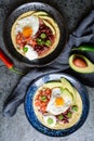 Huevos Rancheros Tostadas, Mexican breakfast consisting of toasted tortilla, chopped tomato and onion, jalapeno and beans, topped