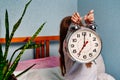 Huge alarm clock in the hands of a child in the bedroom. 7 o'clock in the morning on the clock. Royalty Free Stock Photo