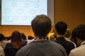 Huge audience looking at the giant screen with chemical structure and listening