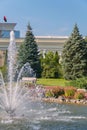A huge beating fountain in the middle of a transparent zera against the background of small flower beds and green spruce Royalty Free Stock Photo