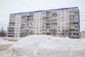 A huge big snowdrift by the road against the backdrop of city houses. Royalty Free Stock Photo