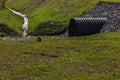 Huge black plastic sewer and small stream Royalty Free Stock Photo