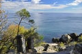 Huge black stones lie in a blue sea on a blue sky with white clouds Royalty Free Stock Photo