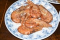 Huge boiled red king prawns lie on blue plate dish