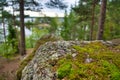 Huge boulders stones covered with moss and pine forest near beatiful fresh blue lake, Park Mon Repos, Vyborg, Russia