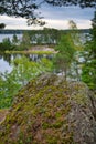 Huge boulders stones covered with moss and pine forest near beatiful fresh blue lake, Park Mon Repos, Vyborg, Russia