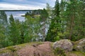 Huge boulders stones covered with moss and pine forest near beatiful fresh blue lake, Park Mon Repos, Vyborg, Russia