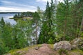 Huge boulders stones covered with moss and pine forest near beatiful fresh blue lake, Park Mon Repos, Vyborg, Russia