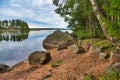 Huge boulders stones covered with moss and pine forest near beatiful fresh blue lake, Park Mon Repos, Vyborg, Russia