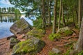 Huge boulders stones covered with moss and pine forest near beatiful fresh blue lake, Park Mon Repos, Vyborg, Russia