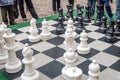 A huge chessboard on which the battle in the tournament children playing with white and black pieces in the open air on the street