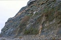 Huge cliff rock mountain on sea coast with stone beach. Royalty Free Stock Photo