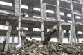A huge concrete beam sticking out of a pile of concrete debris on the background of the destroyed frame of the building