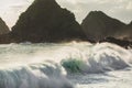 Huge crashing waves in sunset light with mountain view