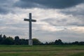 Huge cross in a park with some green trees