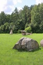 Huge erratic boulders in the megalith park. Big stones lie in the green grass. There are green trees around. Silvarium, a forest p Royalty Free Stock Photo