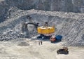 Huge excavator, truck and man standing next on granite quarry