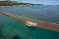 Huge fishing net is pulled up by ropes in a traditional fishing trabucco in Italy