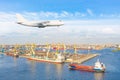 Huge freight airplane landing approach over the cargo seaport