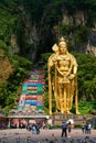 A huge golden statue of Lord Murugan at the entrance with multicolored steps to the Batu Caves Royalty Free Stock Photo