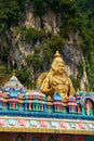 A huge golden statue of Lord Murugan at the entrance with multicolored steps to the Batu Caves Royalty Free Stock Photo