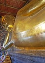 A huge golden statue of a reclining Buddha in a sacred temple