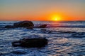 Huge gray rocks amidst dark ocean water with sunset view in San Diego California