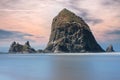 Huge high rock with pink clouds on the horizon in Cannon Beach, Oregon