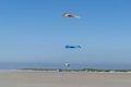 Huge kites flying in a lbue sky on the beach with a van life bus parked underneath Royalty Free Stock Photo