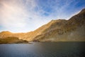 Huge lake in the mountains with a little house on the dock. Nice blue sky with some clouds. Shot in Romania, Transfagarasan