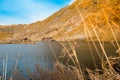 Huge lake in the mountains with a little house on the dock. Nice blue sky with some clouds. Sunny day in Romania, Transfagarasan