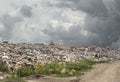 Huge landfill with heavy duty machinery in distance under a dark cloudy sky. Royalty Free Stock Photo