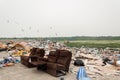 Huge landfill of trash and recycles with old couch in forefront