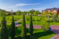 A huge lawn in front of a wooden mansion with stone paths, a green lawn, pyramidal thuja, deciduous trees, a pond with Royalty Free Stock Photo