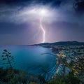 Huge lightning from dark stormy sky strikes coastal city